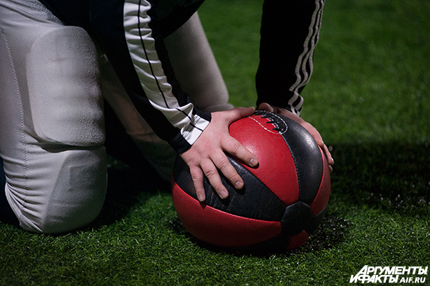 Игрок держит мяч для игры в американский футбол